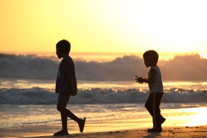 Two brothers play in the waves as the sunsets